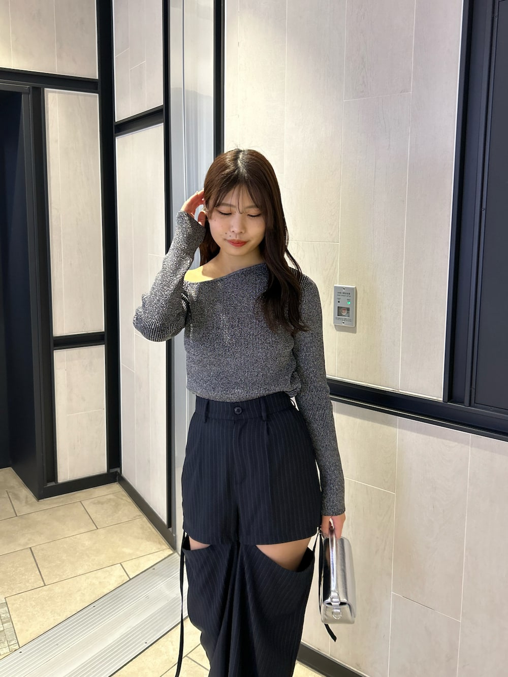 ブラック系のニット/セーター、ブルー系のスラックス、ホワイト系のスニーカーを着用したレディースの春コーディネートの3枚目の写真