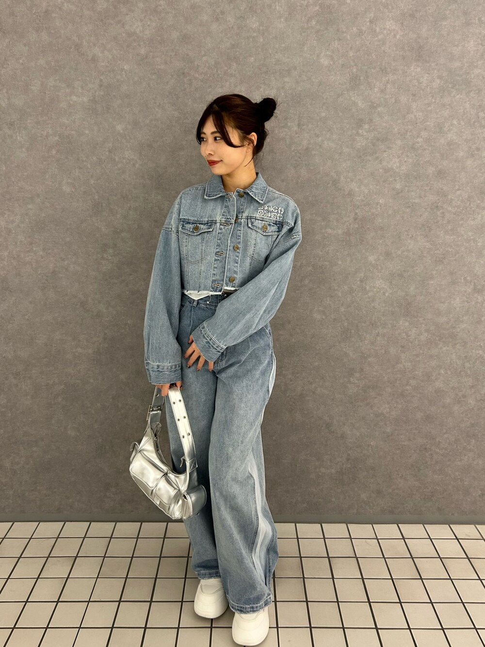 ブルー系のデニムパンツ、ブルー系のデニムジャケット、ホワイト系のキャミソールを着用したレディースの冬コーディネートの2枚目の写真