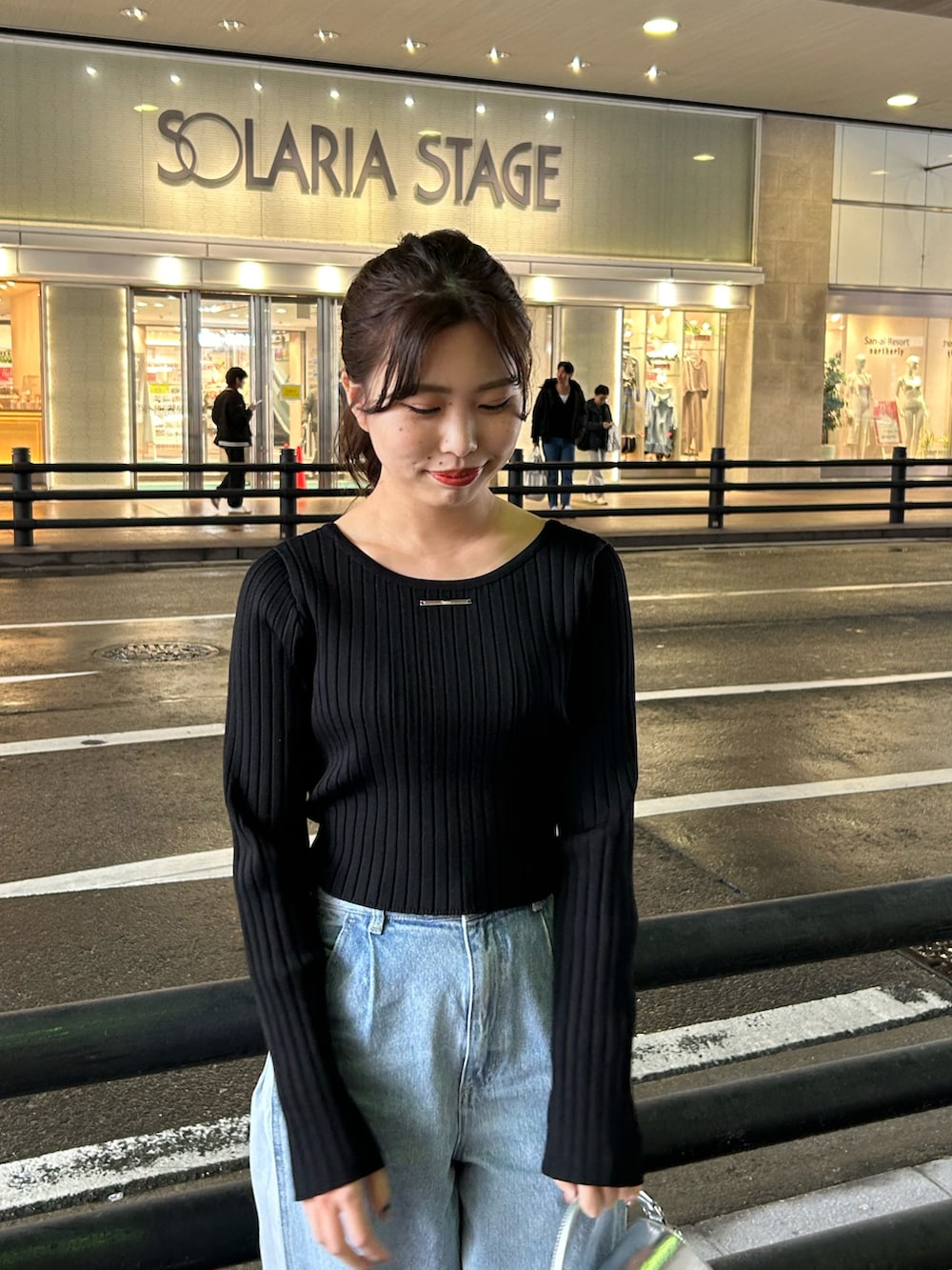 ブルー系のデニムパンツ、ブラック系のニット/セーター、シルバー系のショルダーバッグを着用したレディースの冬コーディネートの3枚目の写真