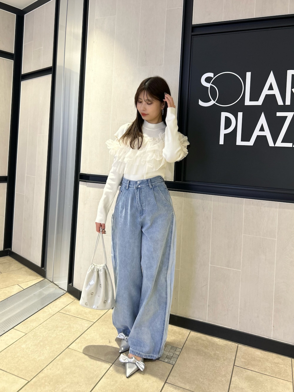 ブルー系のデニムパンツ、ホワイト系のニット/セーター、シルバー系のパンプスを着用したレディースの冬コーディネートの2枚目の写真