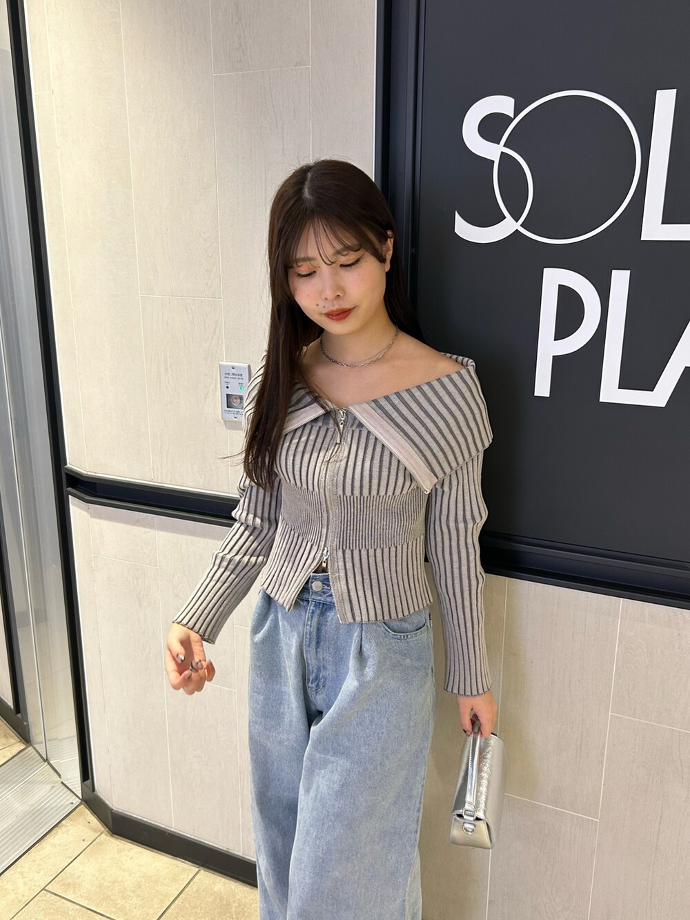 グレー系のニット/セーター、ブルー系のデニムパンツ、シルバー系のショルダーバッグを着用したレディースの春コーディネートの4枚目の写真