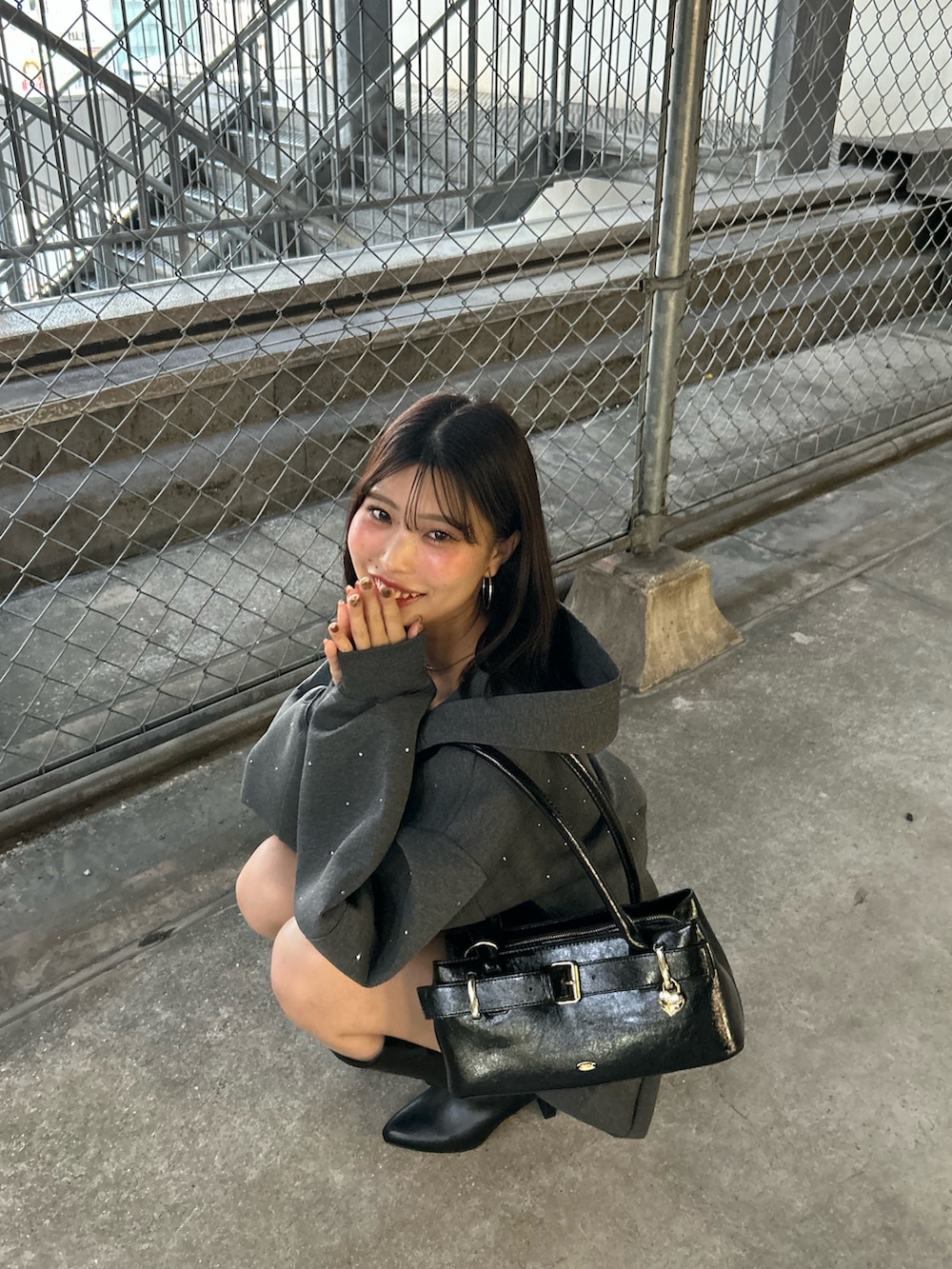 グレー系のパーカー、グレー系のスカート、ブラック系のボストンバッグを着用したレディースの秋コーディネートの7枚目の写真