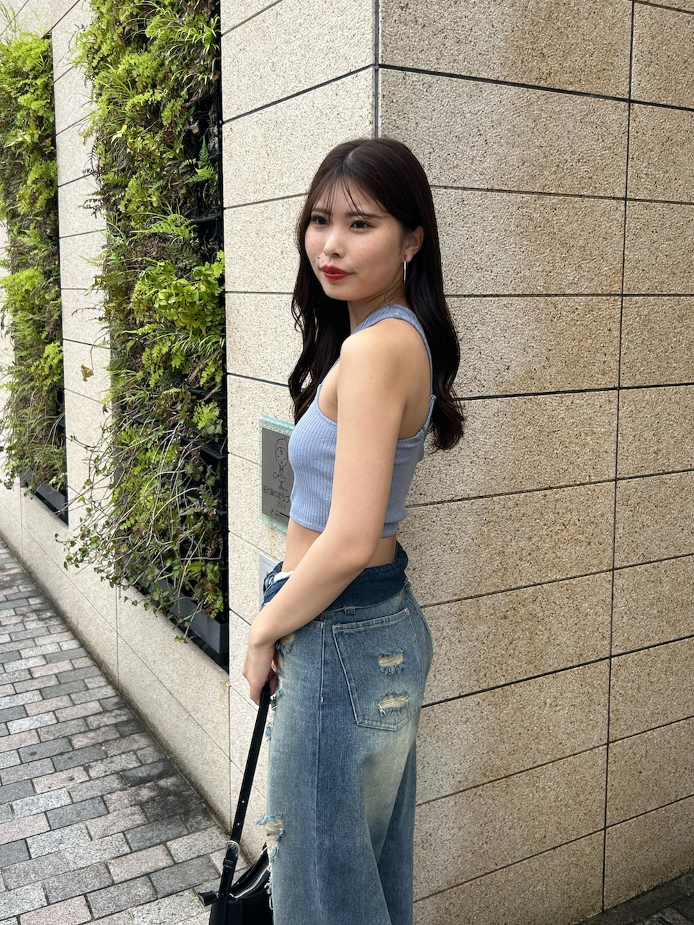 ブルー系のデニムパンツ、ブラック系のショルダーバッグ、ブラック系のサンダルを着用したレディースの春コーディネートの4枚目の写真