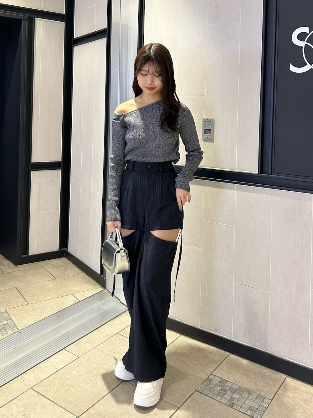 ブラック系のニット/セーター、ブルー系のスラックス、ホワイト系のスニーカーを着用したレディースの春コーディネートの2枚目の写真