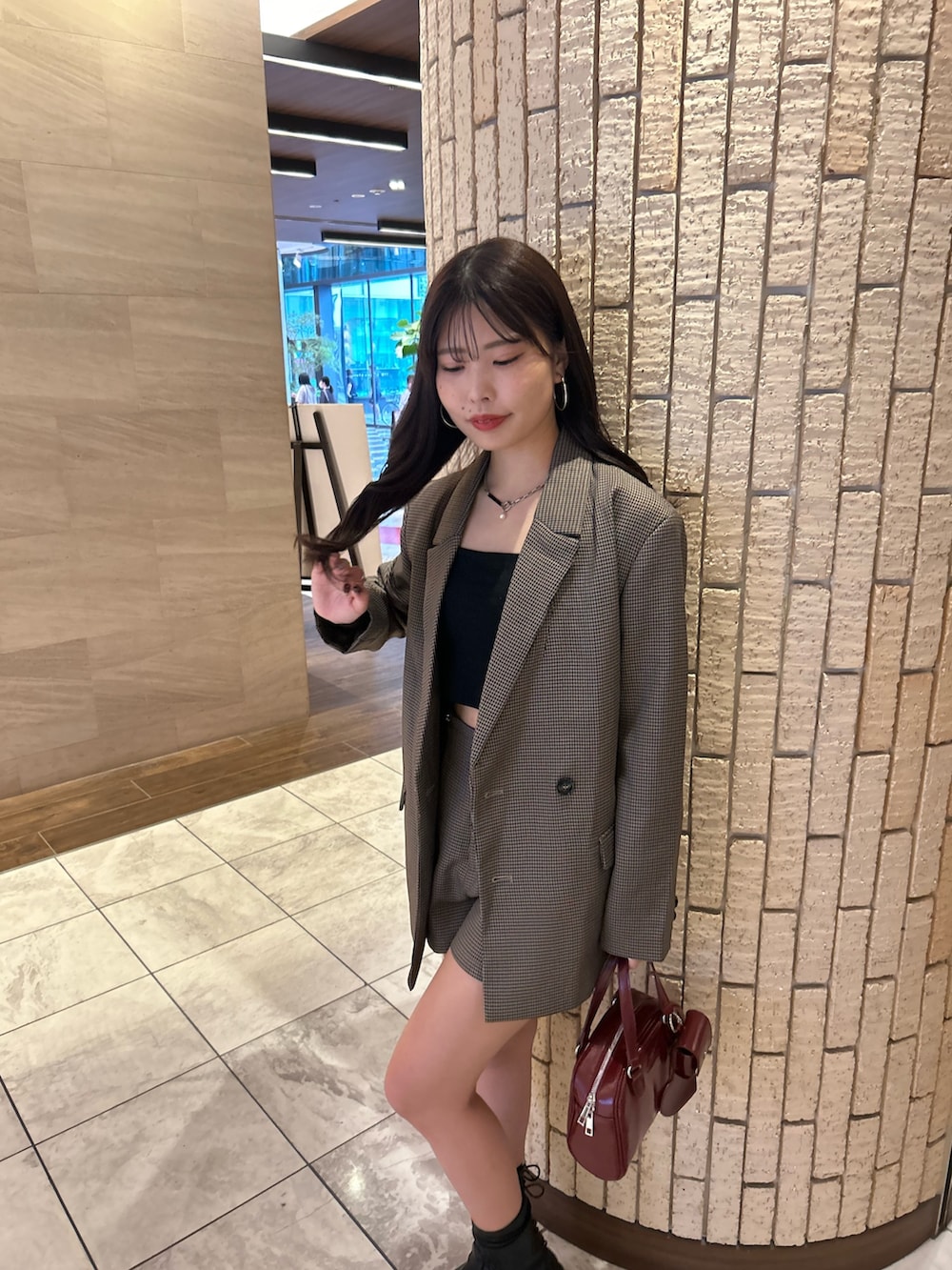 ブラウン系のテーラードジャケット、ブラウン系のその他パンツ、レッド系のボストンバッグを着用したレディースの夏コーディネートの5枚目の写真