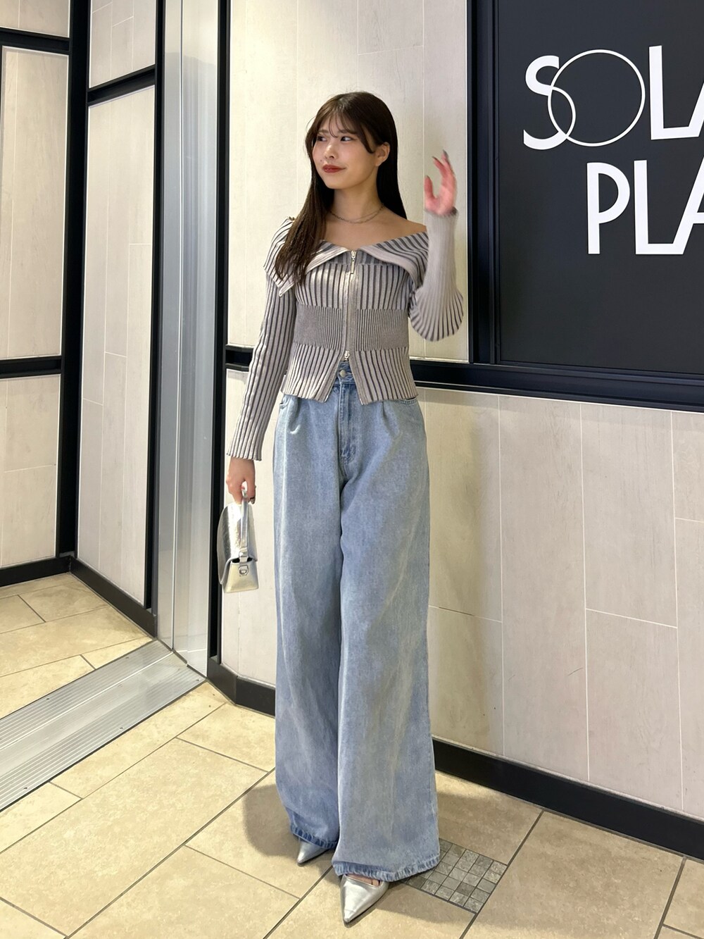 グレー系のニット/セーター、ブルー系のデニムパンツ、シルバー系のショルダーバッグを着用したレディースの春コーディネートの2枚目の写真