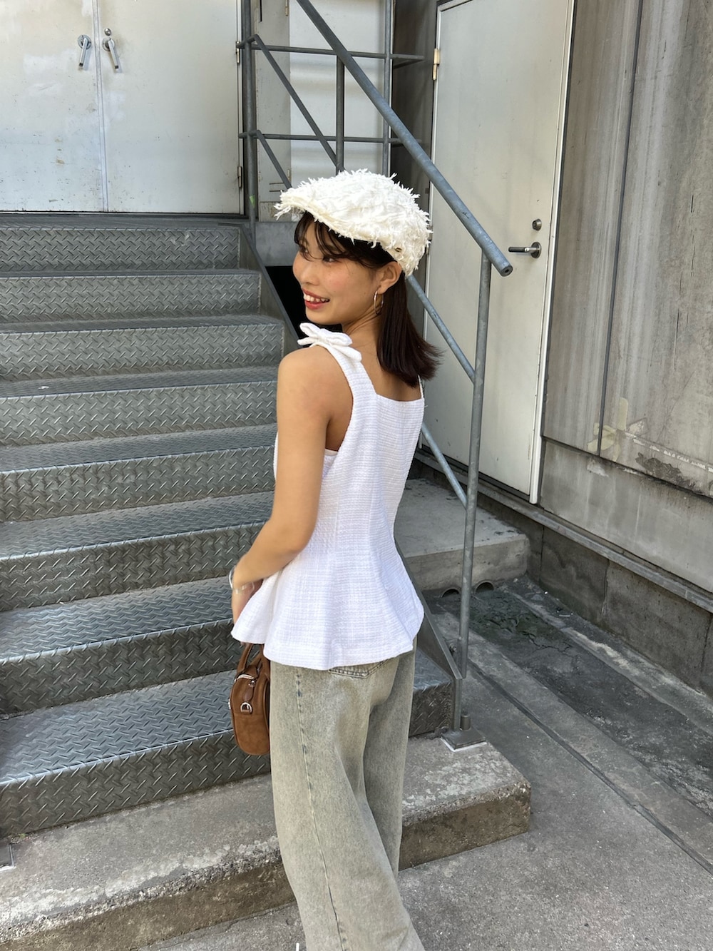 ホワイト系のベスト、ブルー系のデニムパンツ、ブラウン系のボストンバッグを着用したレディースの夏コーディネートの5枚目の写真