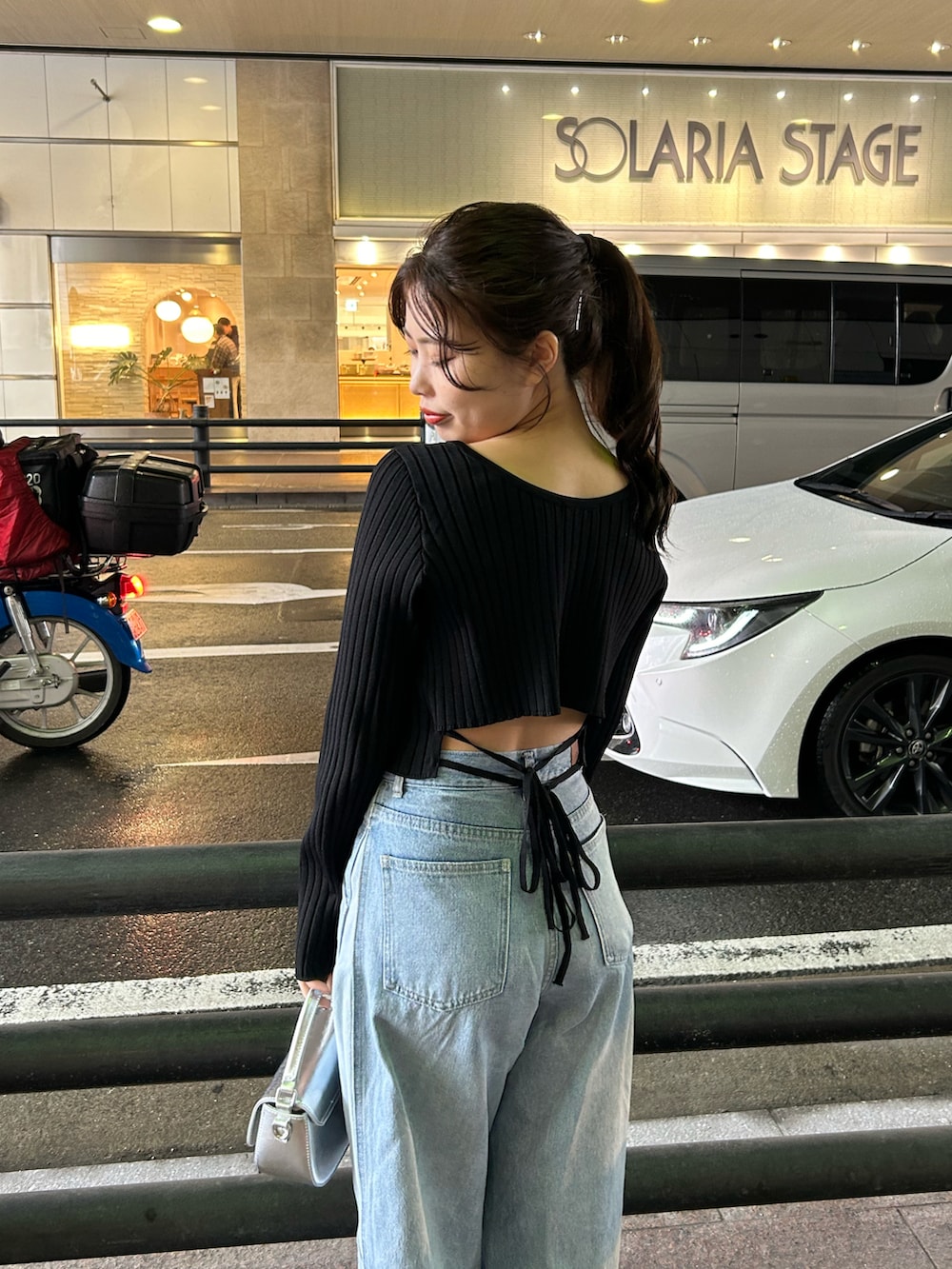 ブルー系のデニムパンツ、ブラック系のニット/セーター、シルバー系のショルダーバッグを着用したレディースの冬コーディネートの4枚目の写真