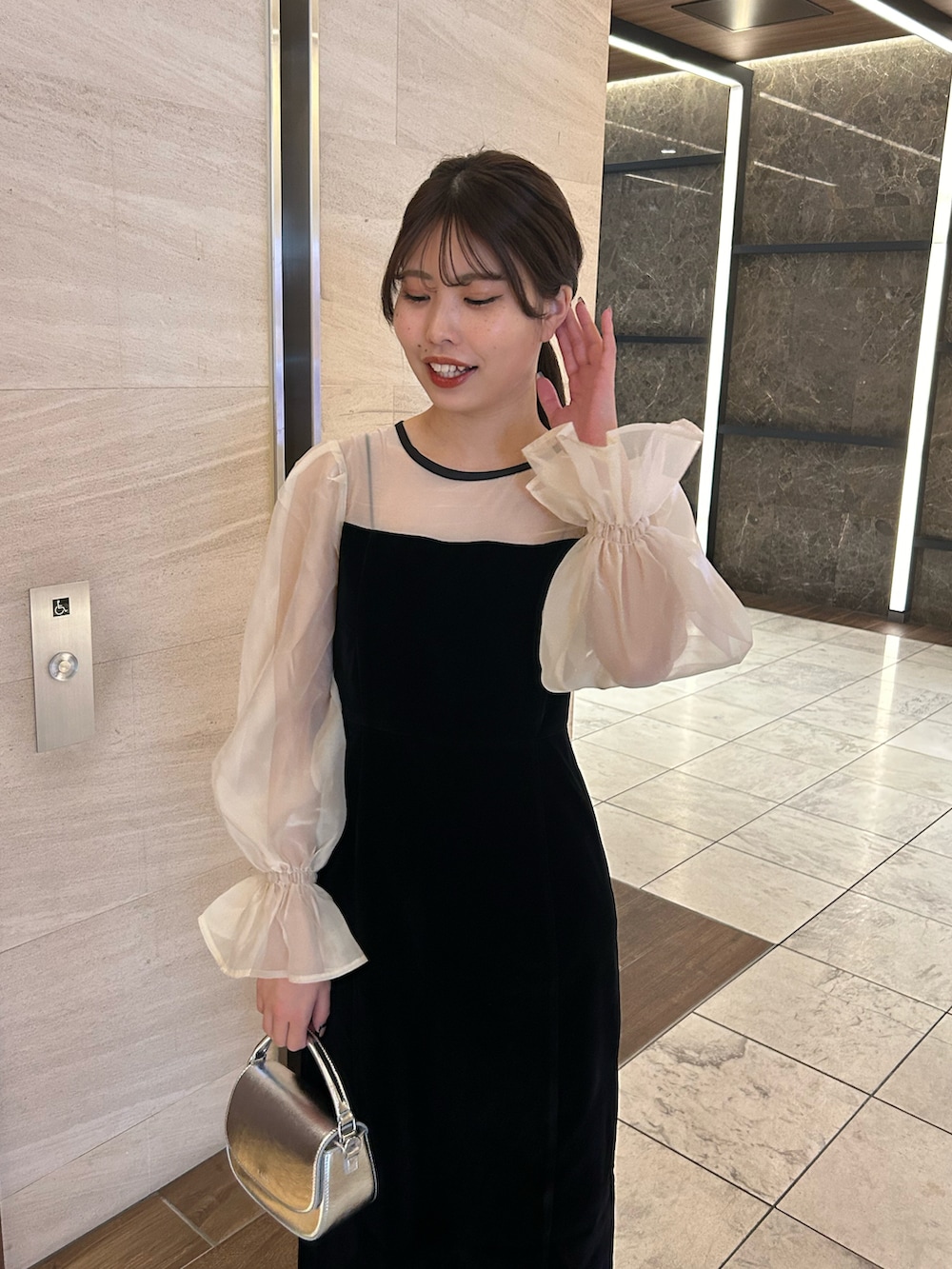 ブラック系のドレス、シルバー系のショルダーバッグ、シルバー系のパンプスを着用したレディースの春コーディネートの4枚目の写真