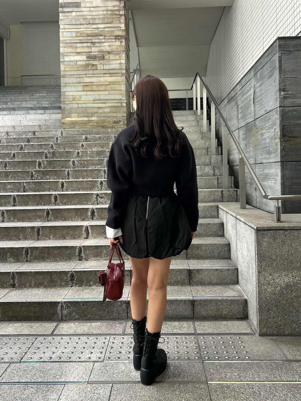 ブラック系のニット/セーター、レッド系のボストンバッグを着用したレディースの夏コーディネートの3枚目の写真