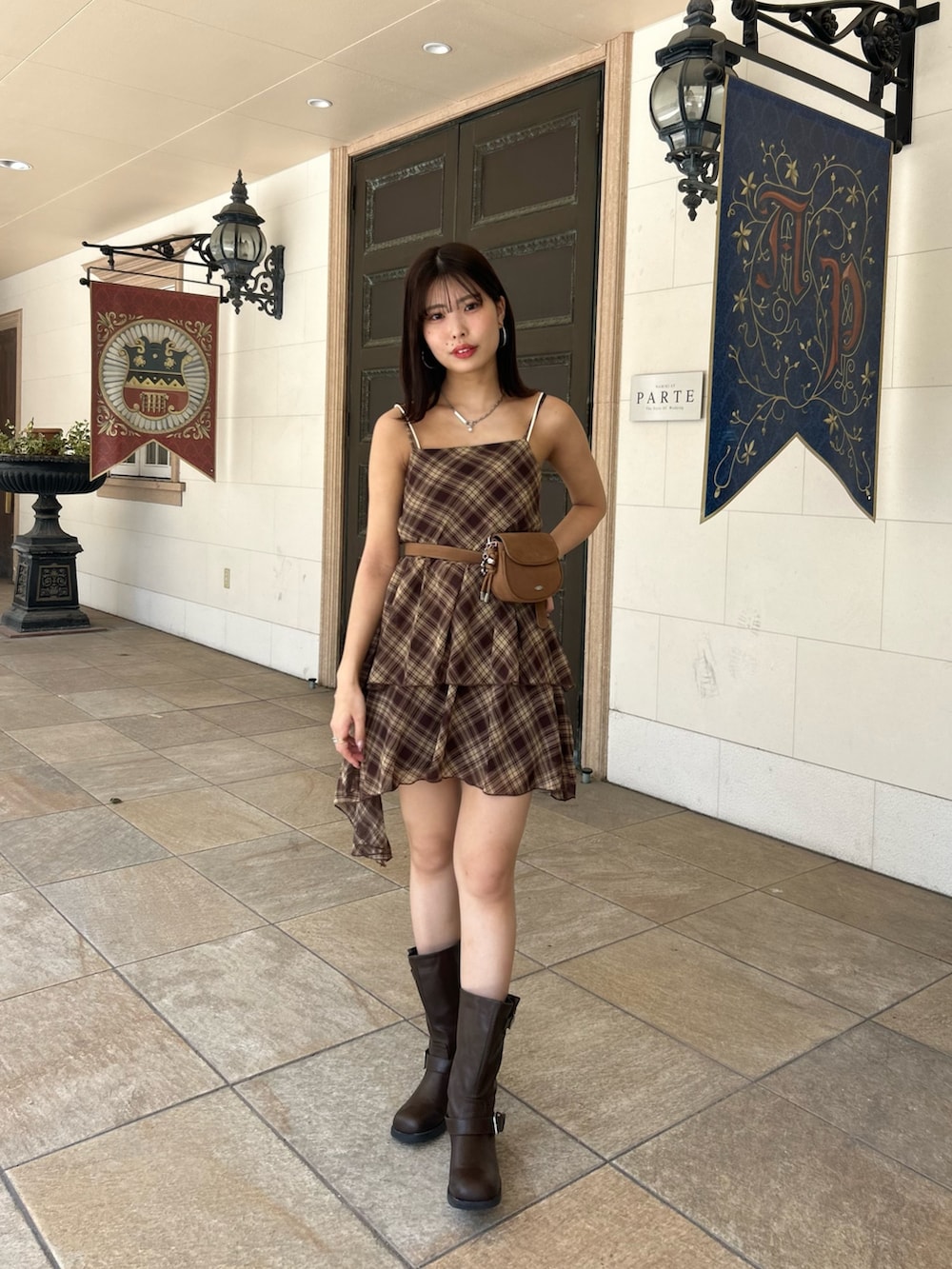 ブラウン系のワンピース、ブラウン系のブーツ、ホワイト系のキャミソールを着用したレディースの夏コーディネートの2枚目の写真