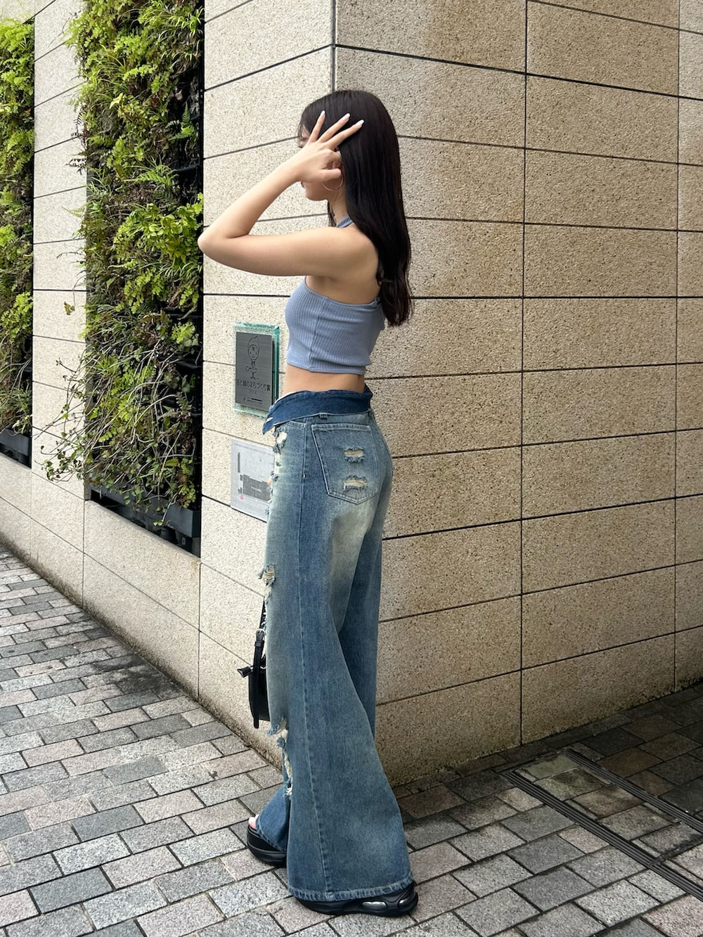 ブルー系のデニムパンツ、ブラック系のショルダーバッグ、ブラック系のサンダルを着用したレディースの春コーディネートの2枚目の写真