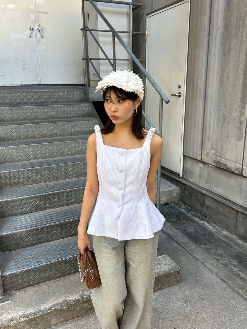 ホワイト系のベスト、ブルー系のデニムパンツ、ブラウン系のボストンバッグを着用したレディースの夏コーディネートの4枚目の写真