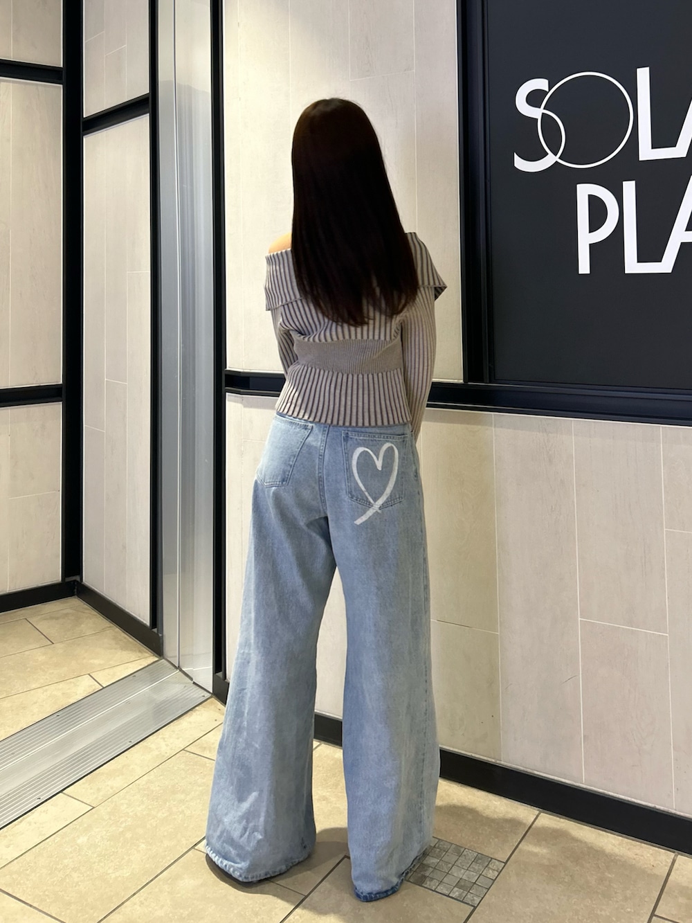 グレー系のニット/セーター、ブルー系のデニムパンツ、シルバー系のショルダーバッグを着用したレディースの春コーディネートの3枚目の写真