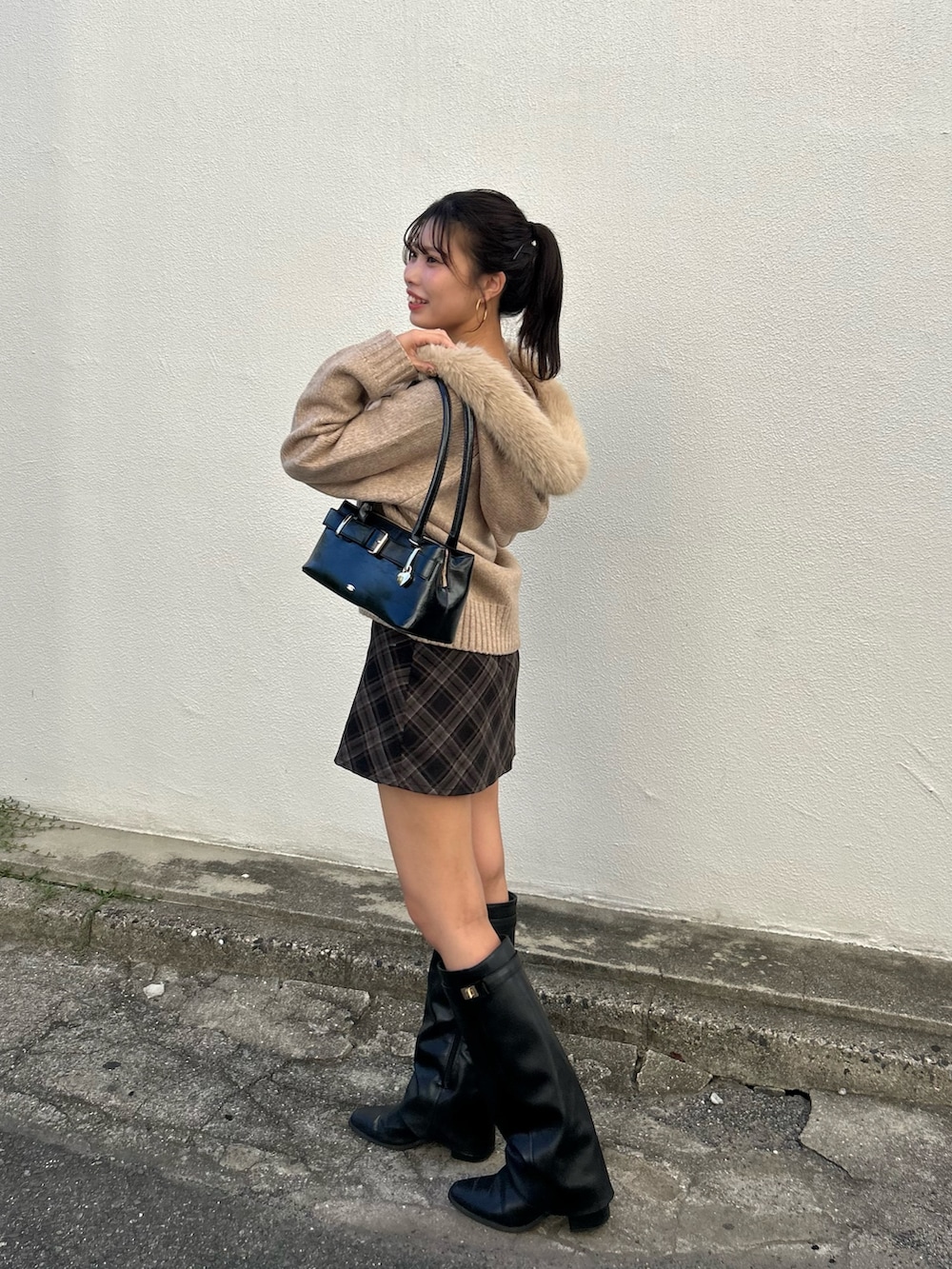 ベージュ系のニット/セーター、グレー系のスカート、ブラック系のボストンバッグを着用したレディースの秋コーディネートの2枚目の写真