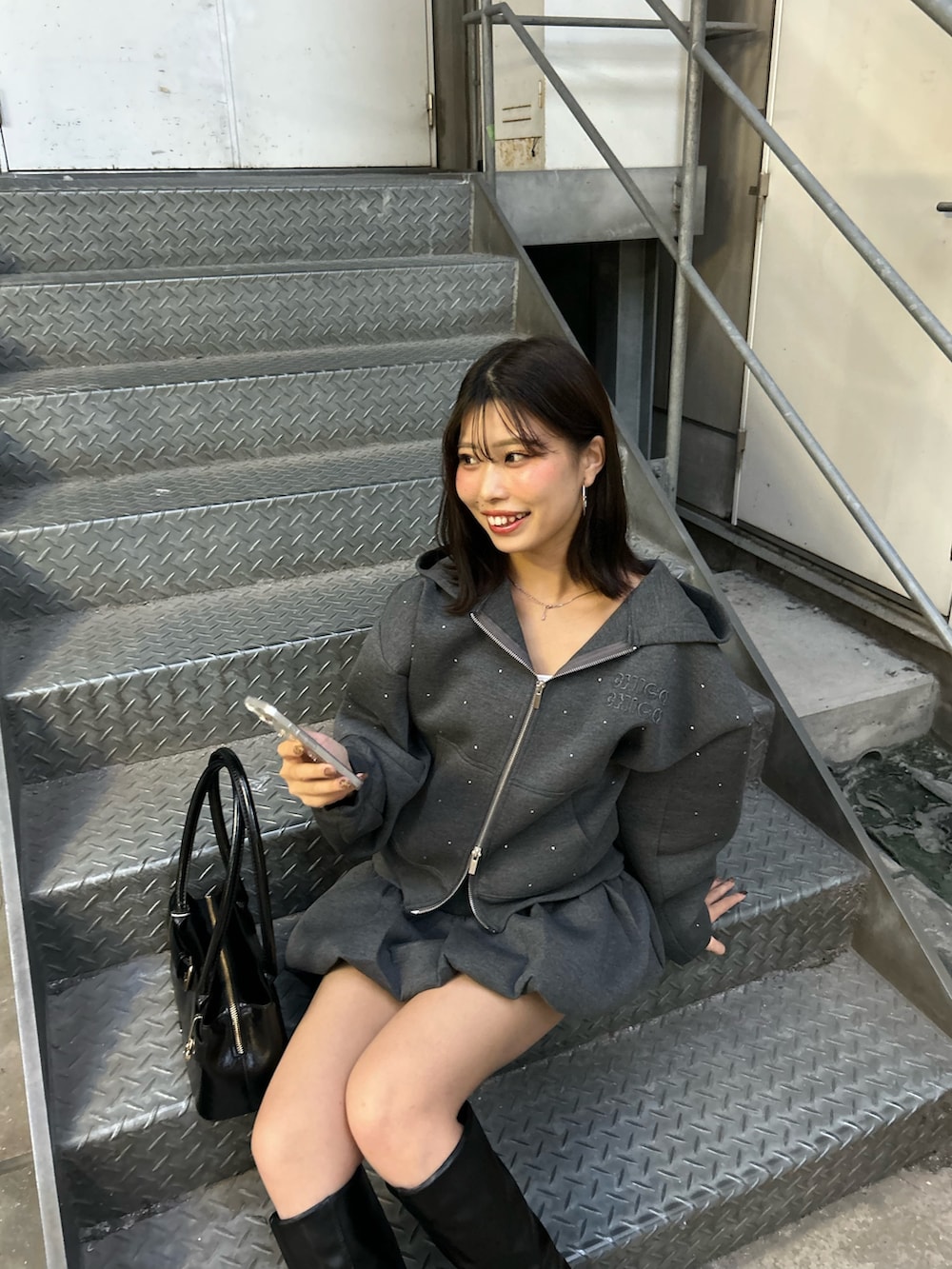 グレー系のパーカー、グレー系のスカート、ブラック系のボストンバッグを着用したレディースの秋コーディネートの5枚目の写真