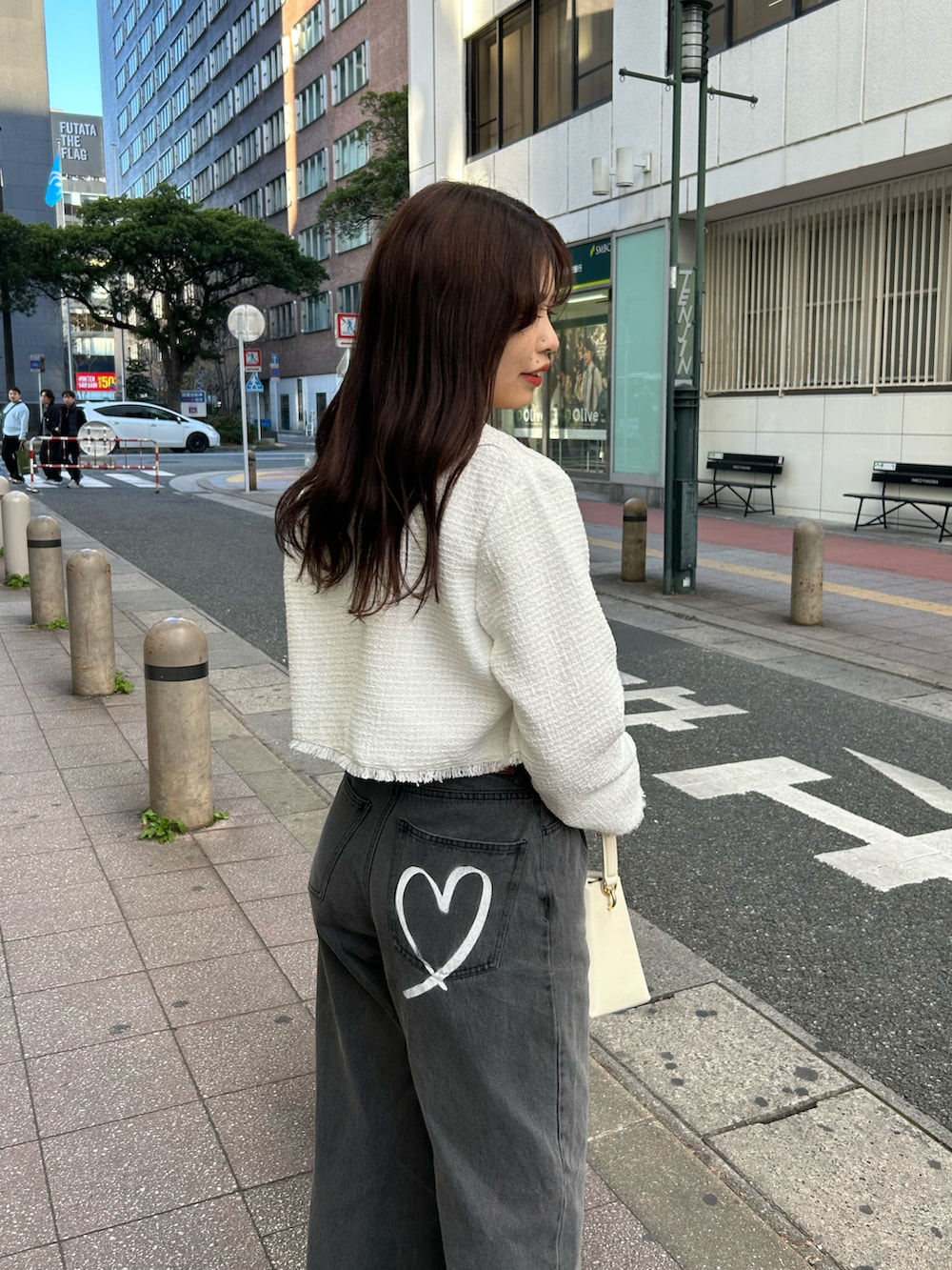 グレー系のデニムパンツ、ホワイト系のノーカラージャケット、ホワイト系のショルダーバッグを着用したレディースの冬コーディネートの3枚目の写真