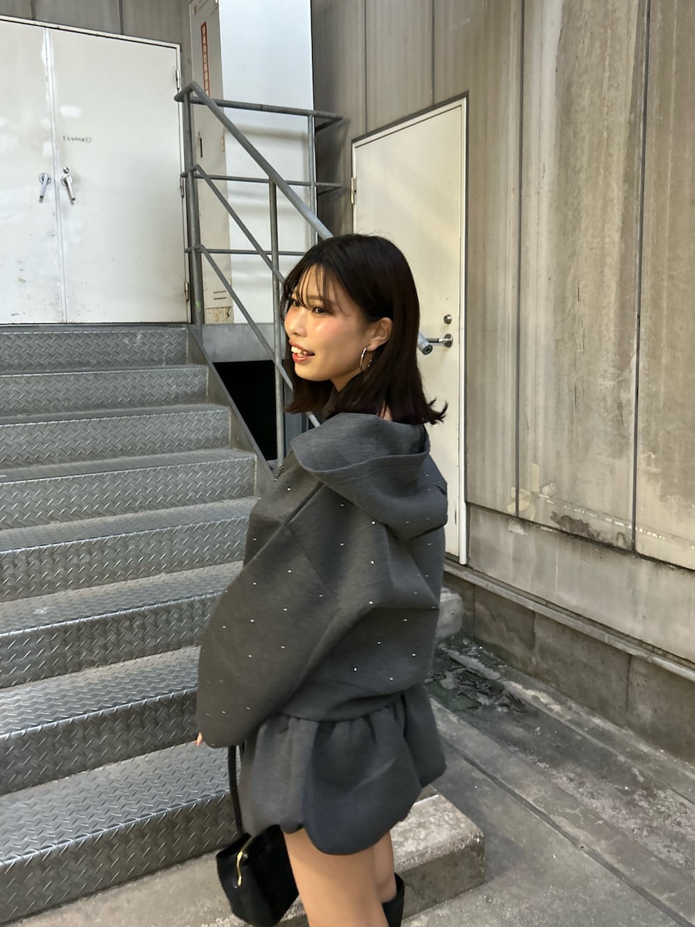 グレー系のパーカー、グレー系のスカート、ブラック系のボストンバッグを着用したレディースの秋コーディネートの4枚目の写真