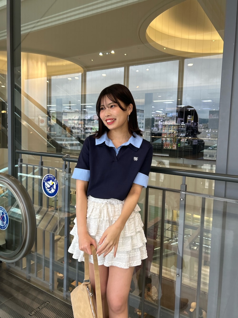 ブルー系のニット/セーター、ホワイト系のその他パンツ、ベージュ系のショルダーバッグを着用したレディースの春コーディネートの4枚目の写真