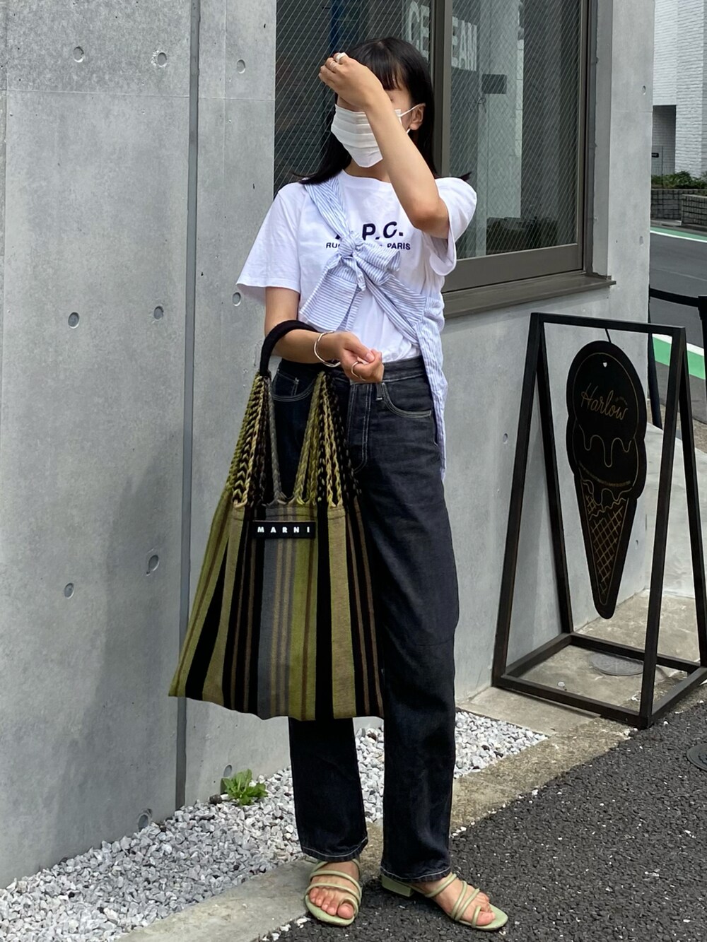 グリーン系のサンダル、ブラック系のデニムパンツ、グリーン系のトートバッグを着用したレディースの夏コーディネートの2枚目の写真