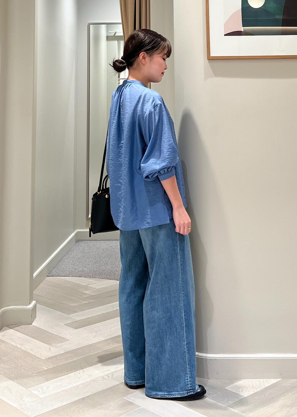 ブラック系のハンドバッグ、ブルー系のデニムパンツ、ブルー系のシャツ/ブラウスを着用したレディースの夏コーディネートの3枚目の写真