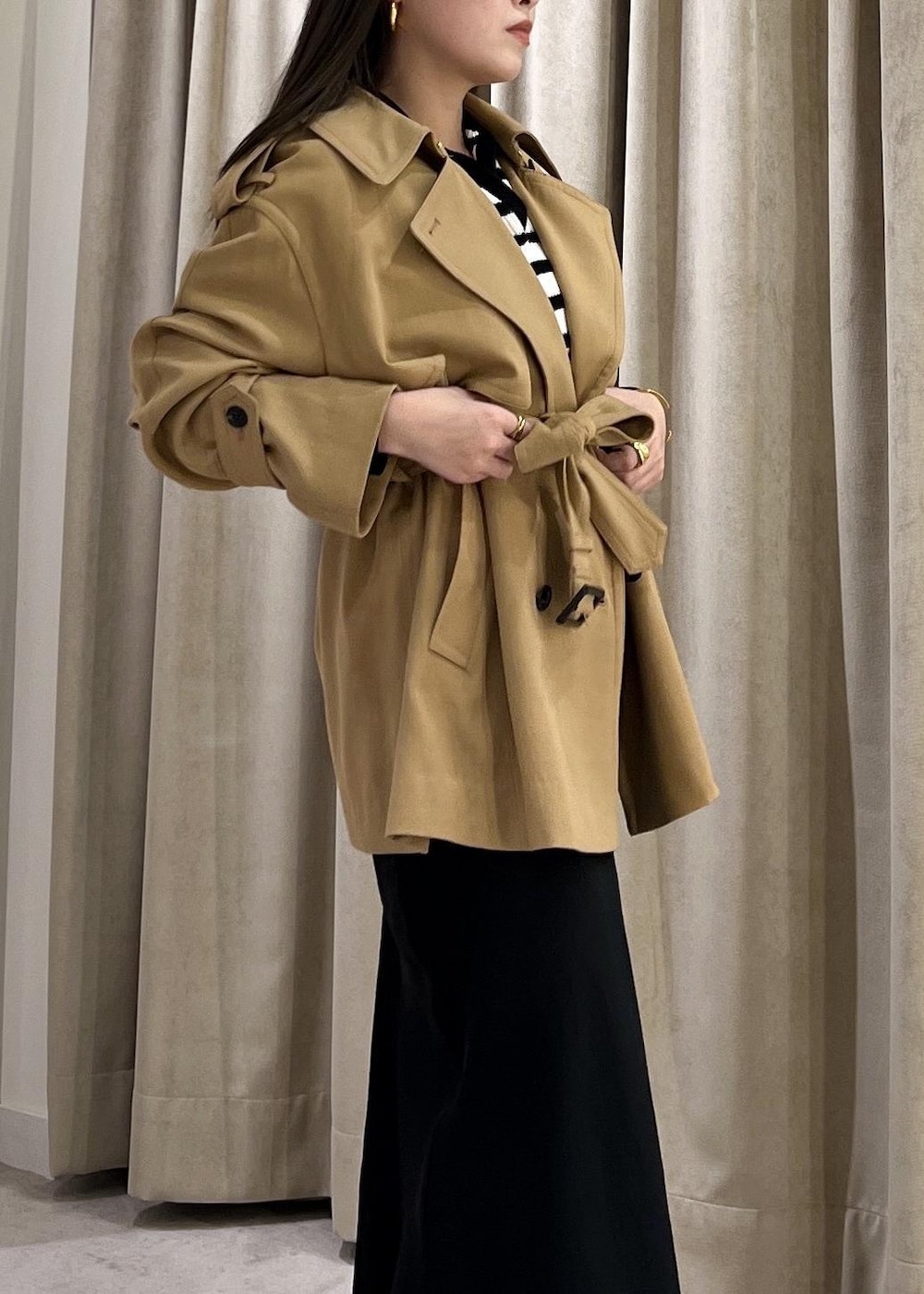 ブラック系のスカート、ベージュ系のトレンチコート、ホワイト系のニット/セーターを着用したレディースの冬コーディネートの9枚目の写真