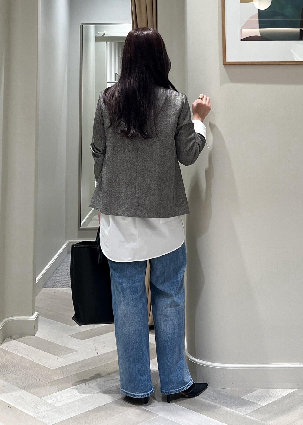 ブラック系のパンプス、ブルー系のデニムパンツ、ブラック系のトートバッグを着用したレディースの秋コーディネートの5枚目の写真