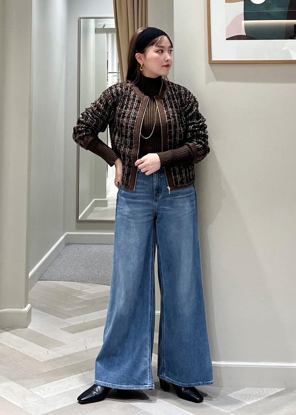 ブルー系のデニムパンツ、ブラック系のブーツ、ブラウン系のニット/セーターを着用したレディースの秋コーディネートの2枚目の写真