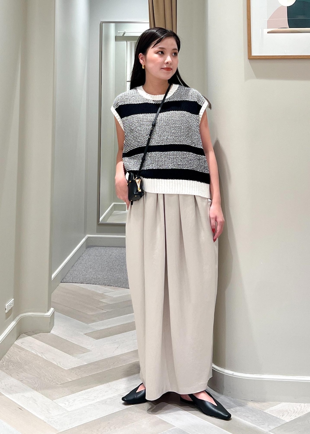 ブラック系のパンプス、ブラック系のショルダーバッグ、ベージュ系のワンピースを着用したレディースの夏コーディネートの2枚目の写真