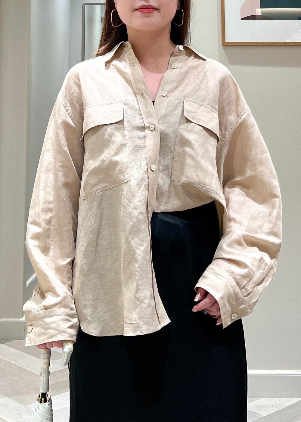 ブラック系のスカート、ベージュ系のシャツ/ブラウス、ホワイト系の長傘を着用したレディースの夏コーディネートの6枚目の写真