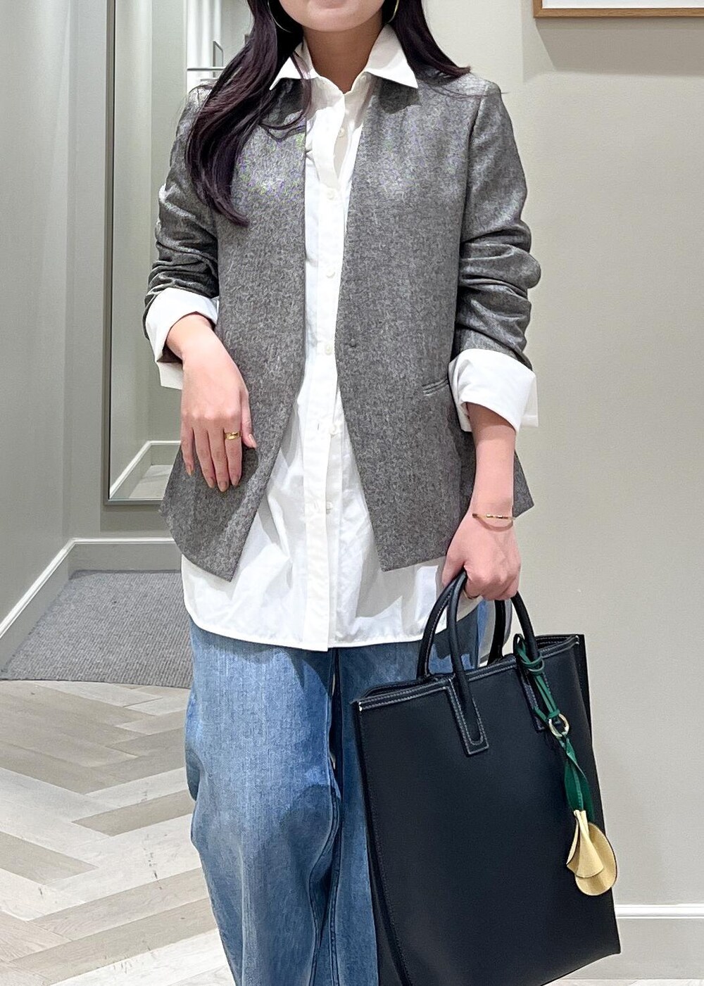 ブラック系のパンプス、ブルー系のデニムパンツ、ブラック系のトートバッグを着用したレディースの秋コーディネートの8枚目の写真