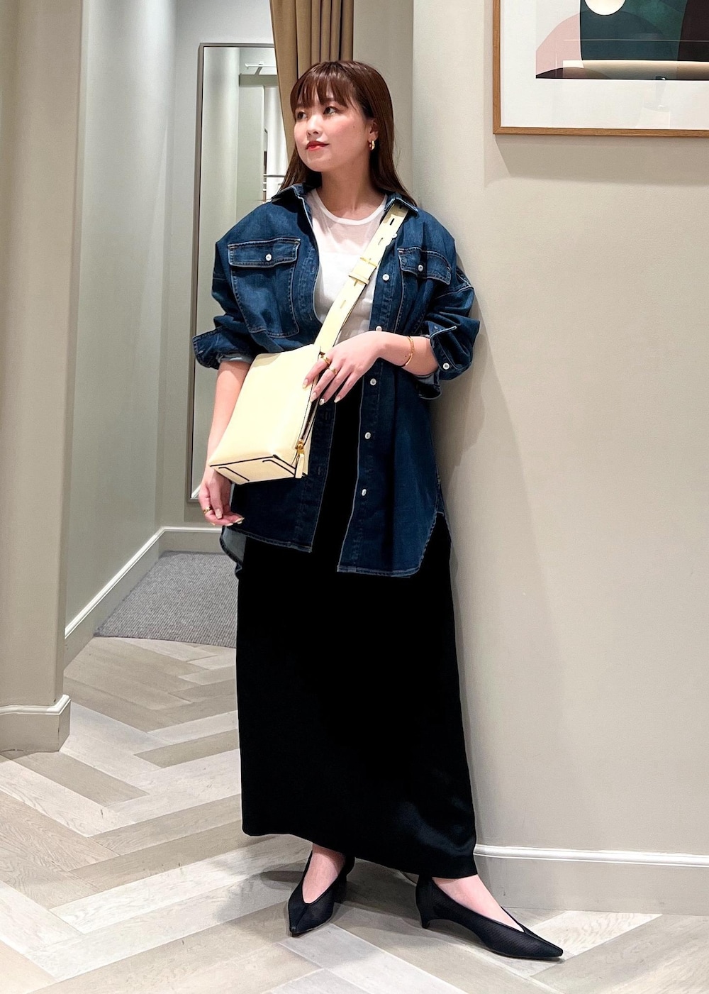 ホワイト系のショルダーバッグ、ブラック系のパンプス、ブラック系のスカートを着用したレディースの夏コーディネートの2枚目の写真