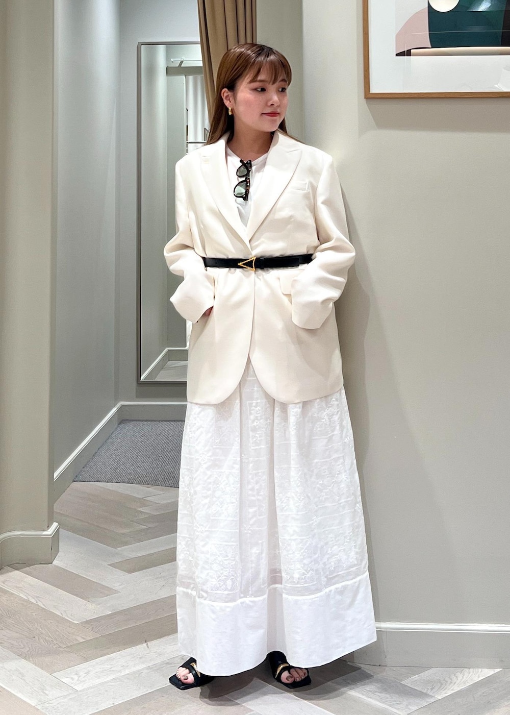 ホワイト系のテーラードジャケット、ブラック系のサンダル、ホワイト系のワンピースを着用したレディースの春コーディネートの2枚目の写真