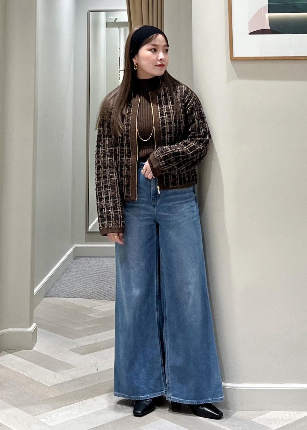 ブルー系のデニムパンツ、ブラック系のブーツ、ブラウン系のニット/セーターを着用したレディースの秋コーディネートの6枚目の写真