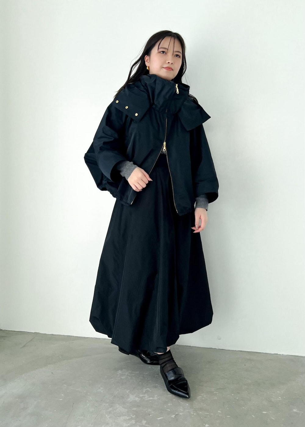 グレー系のニット/セーター、ブルー系のマウンテンパーカー、ブラック系のパンプスを着用したレディースの冬コーディネートの2枚目の写真