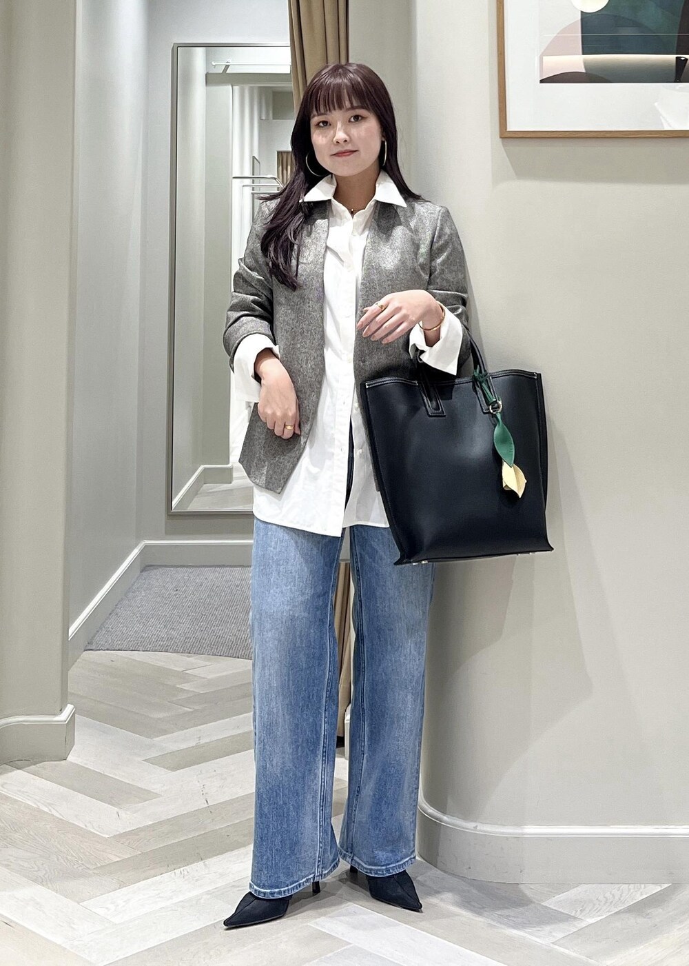 ブラック系のパンプス、ブルー系のデニムパンツ、ブラック系のトートバッグを着用したレディースの秋コーディネートの3枚目の写真