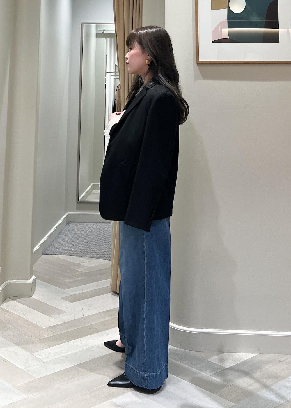 ブルー系のデニムパンツ、ブラック系のテーラードジャケット、ブラック系のベルトを着用したレディースの冬コーディネートの4枚目の写真