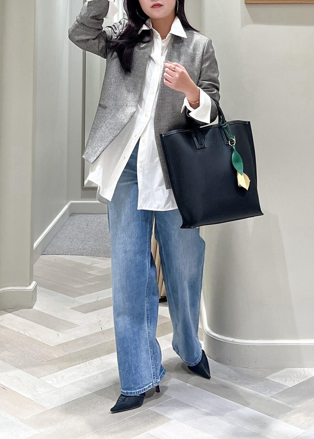 ブラック系のパンプス、ブルー系のデニムパンツ、ブラック系のトートバッグを着用したレディースの秋コーディネートの7枚目の写真