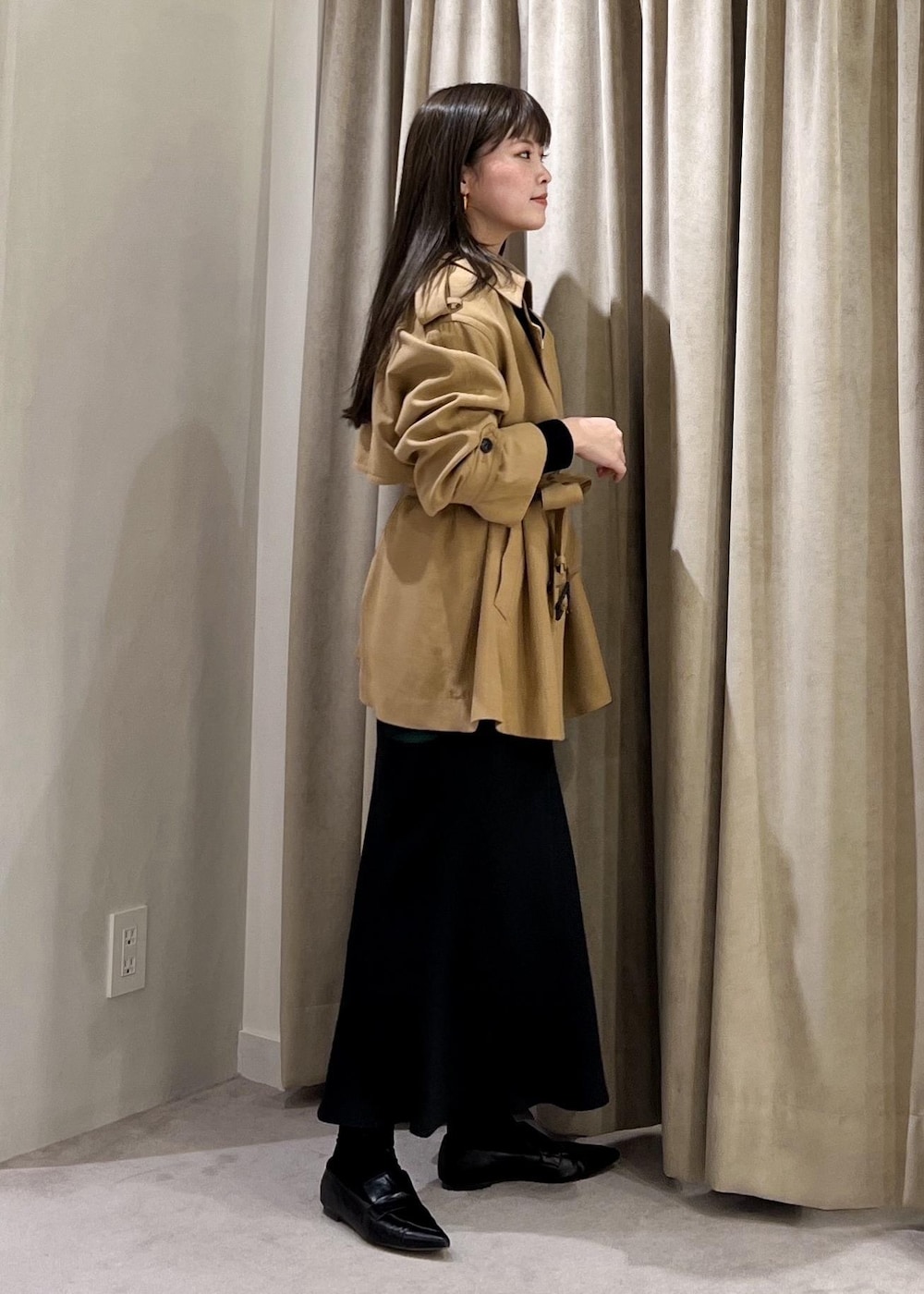 ブラック系のスカート、ベージュ系のトレンチコート、ホワイト系のニット/セーターを着用したレディースの冬コーディネートの6枚目の写真
