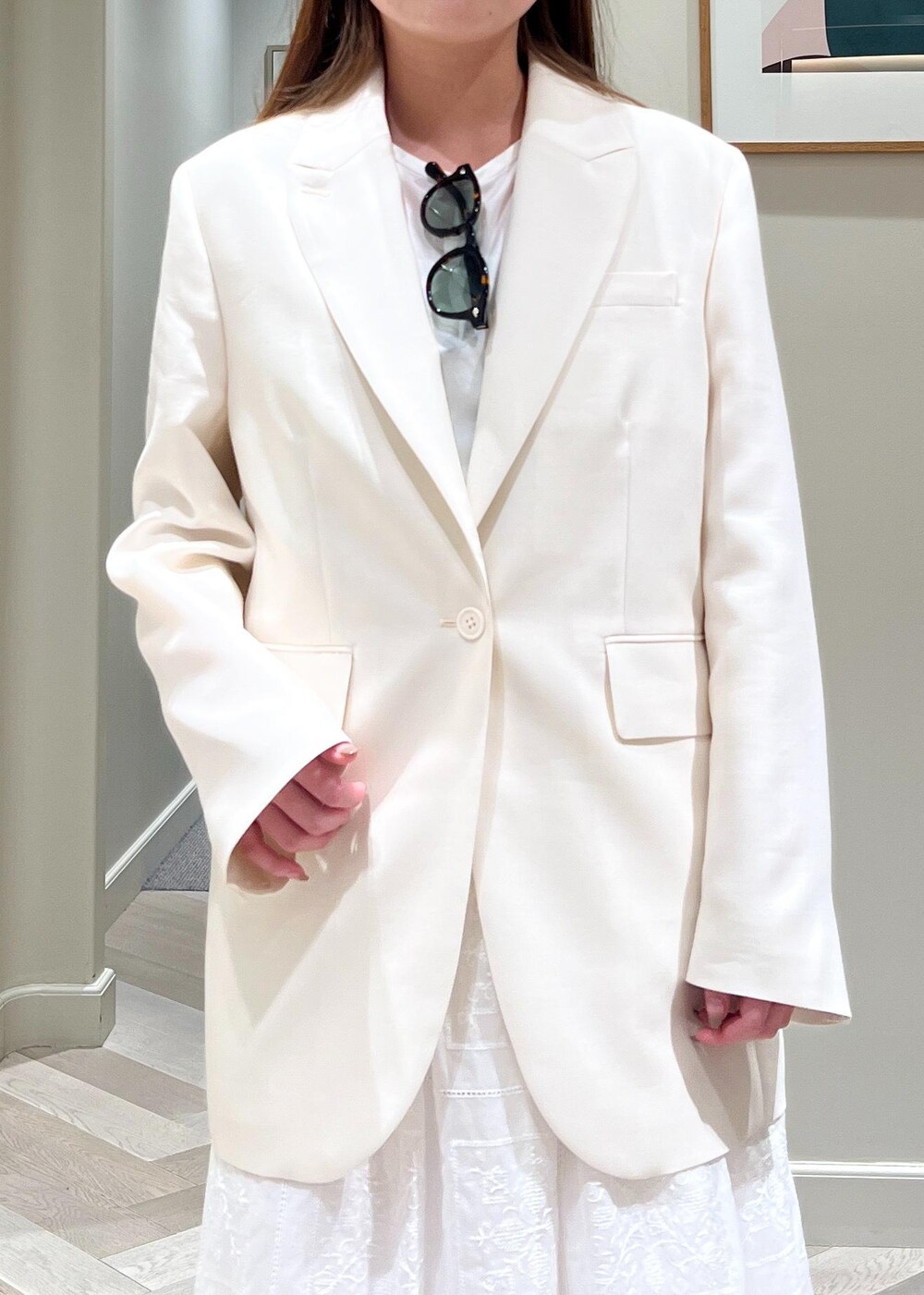 ホワイト系のテーラードジャケット、ブラック系のサンダル、ホワイト系のワンピースを着用したレディースの春コーディネートの6枚目の写真