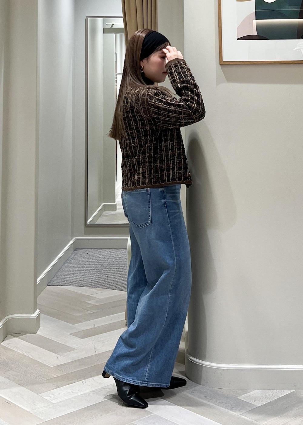 ブルー系のデニムパンツ、ブラック系のブーツ、ブラウン系のニット/セーターを着用したレディースの秋コーディネートの4枚目の写真