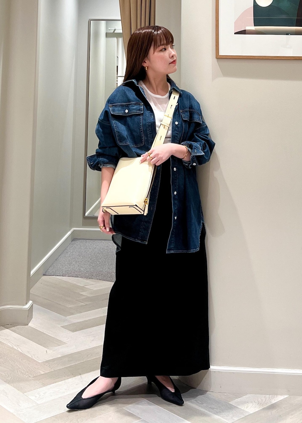 ホワイト系のショルダーバッグ、ブラック系のパンプス、ブラック系のスカートを着用したレディースの夏コーディネートの3枚目の写真