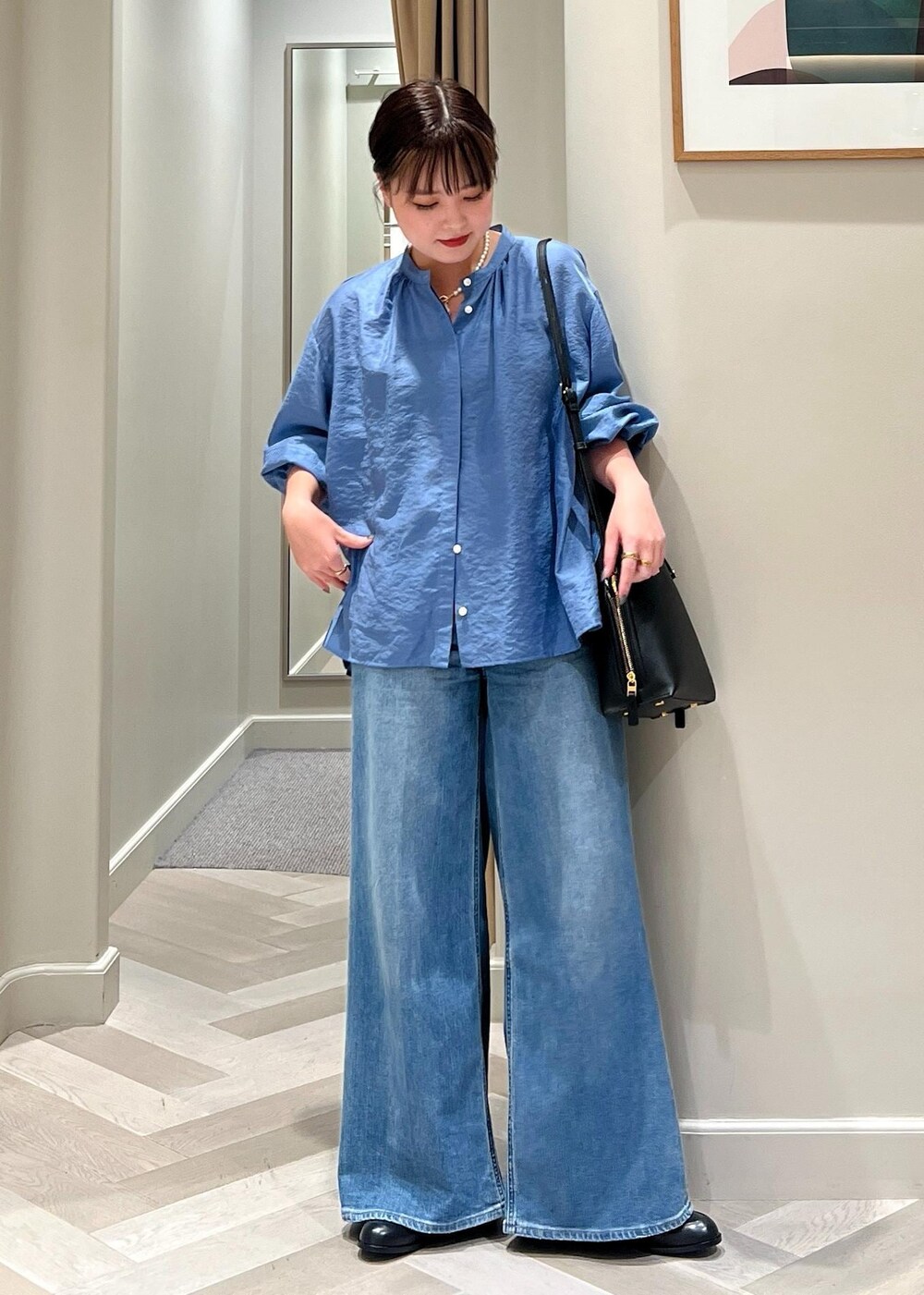 ブラック系のハンドバッグ、ブルー系のデニムパンツ、ブルー系のシャツ/ブラウスを着用したレディースの夏コーディネートの5枚目の写真