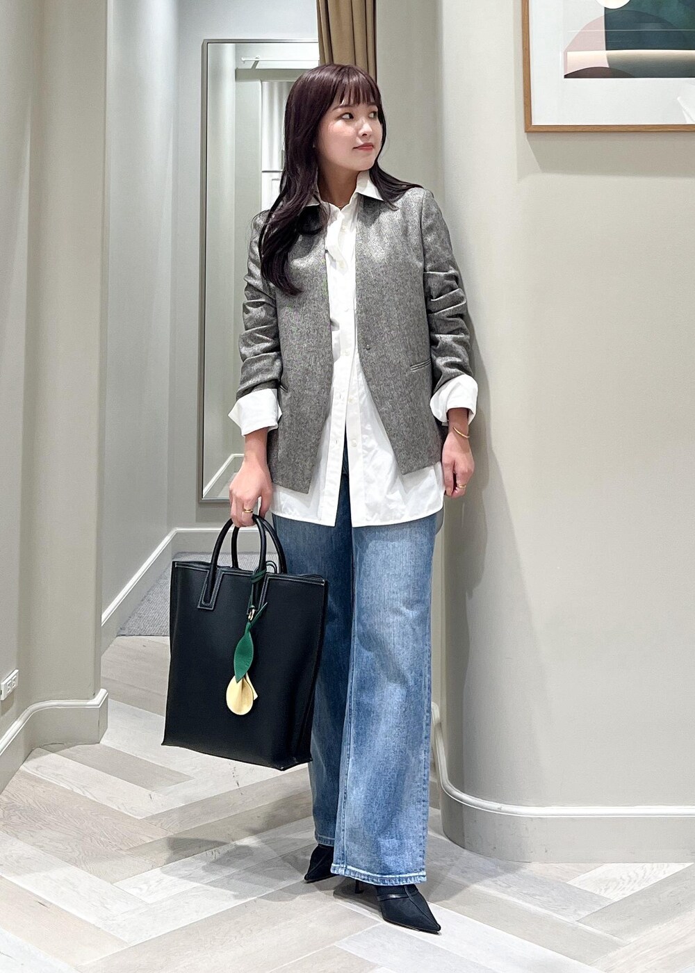ブラック系のパンプス、ブルー系のデニムパンツ、ブラック系のトートバッグを着用したレディースの秋コーディネートの6枚目の写真