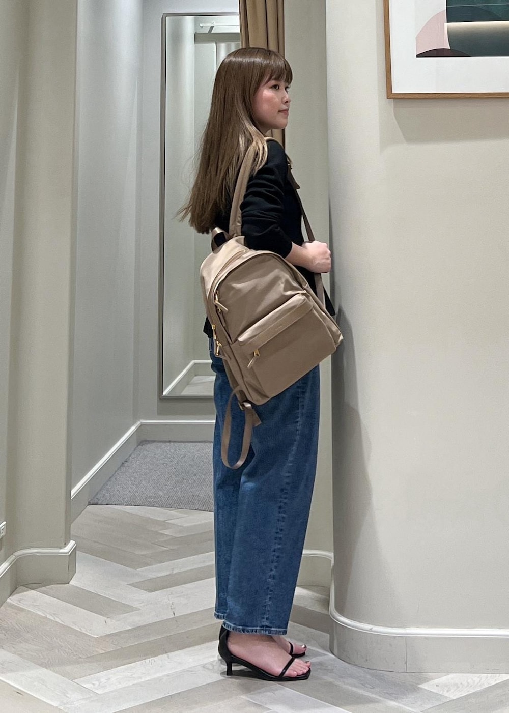 ブラック系のニット/セーター、ベージュ系のバックパック/リュック、ブルー系のデニムパンツを着用したレディースの冬コーディネートの4枚目の写真