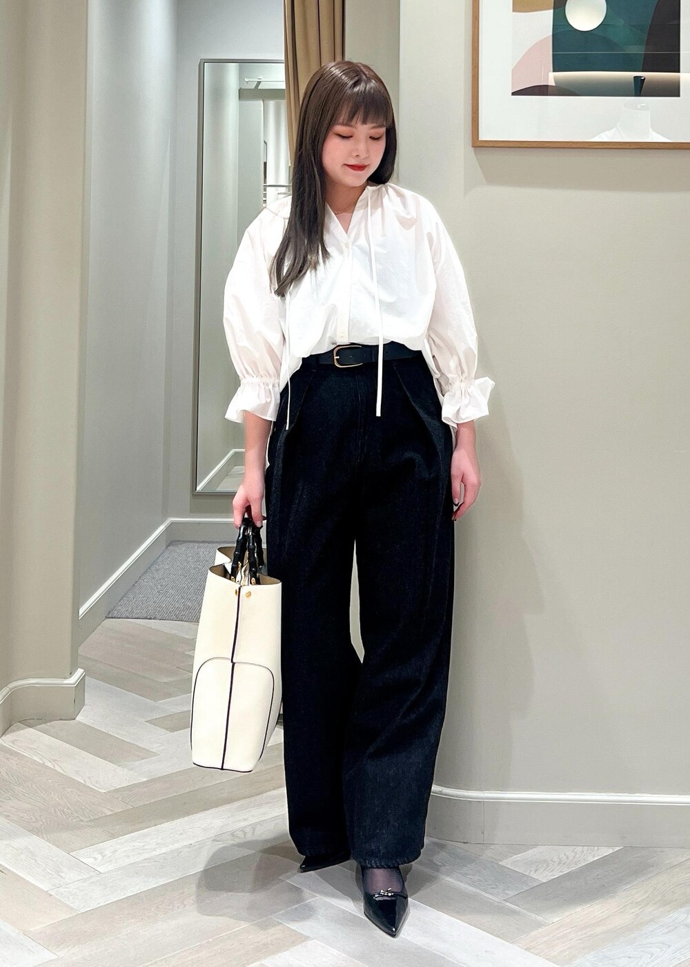 ブラック系のパンプス、ホワイト系のシャツ/ブラウス、ブラック系のデニムパンツを着用したレディースの春コーディネートの2枚目の写真