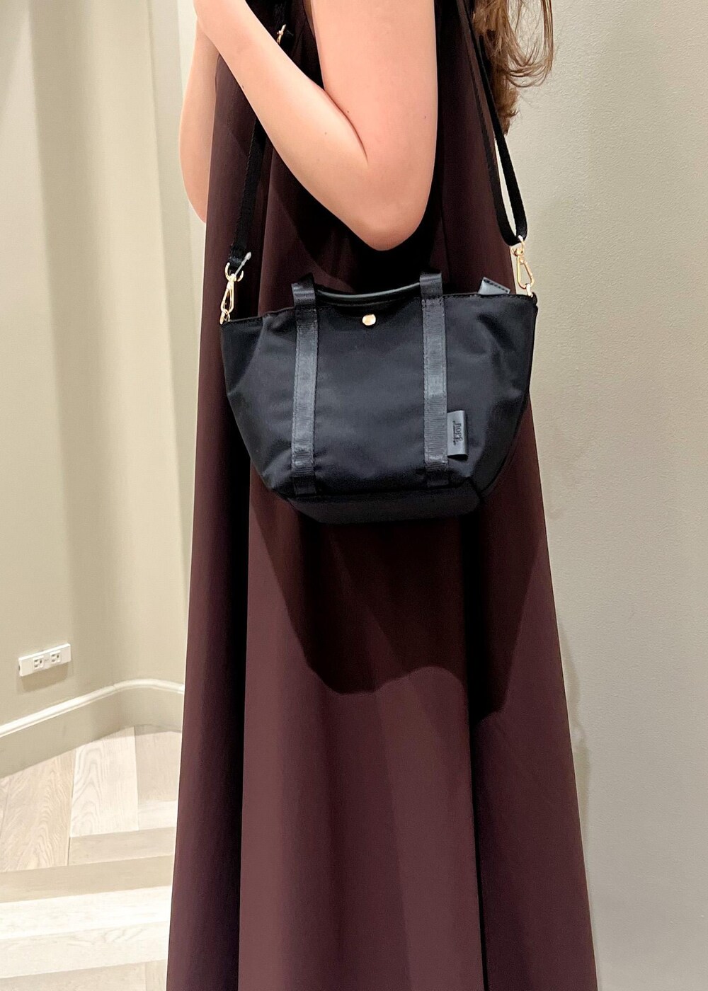 ブラック系のトートバッグ、ブラウン系のワンピース、ブラック系のサンダルを着用したレディースの夏コーディネートの6枚目の写真