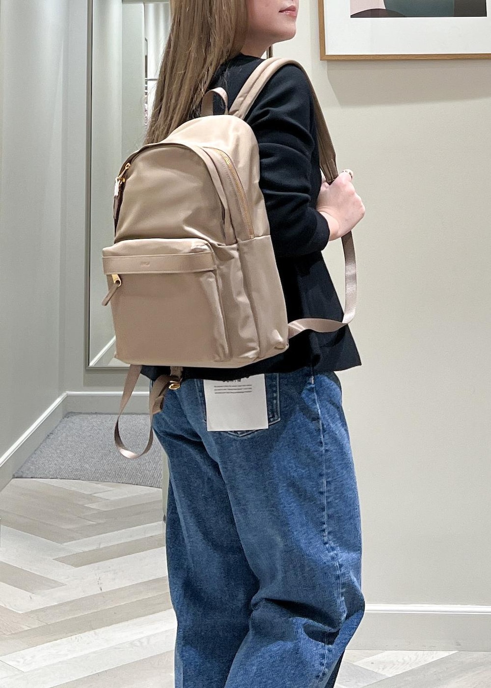 ブラック系のニット/セーター、ベージュ系のバックパック/リュック、ブルー系のデニムパンツを着用したレディースの冬コーディネートの8枚目の写真