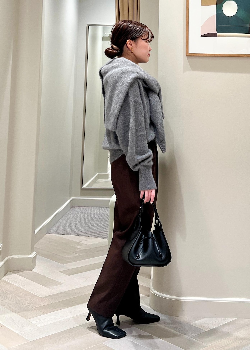 ブラック系のハンドバッグ、ブラック系のブーツ、グレー系のカーディガン/ボレロを着用したレディースの秋コーディネートの3枚目の写真