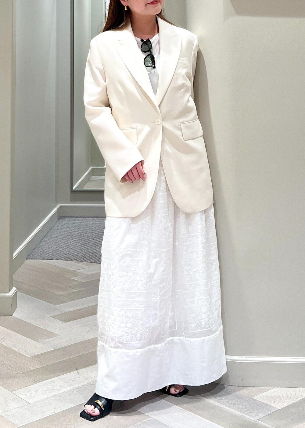 ホワイト系のテーラードジャケット、ブラック系のサンダル、ホワイト系のワンピースを着用したレディースの春コーディネートの8枚目の写真